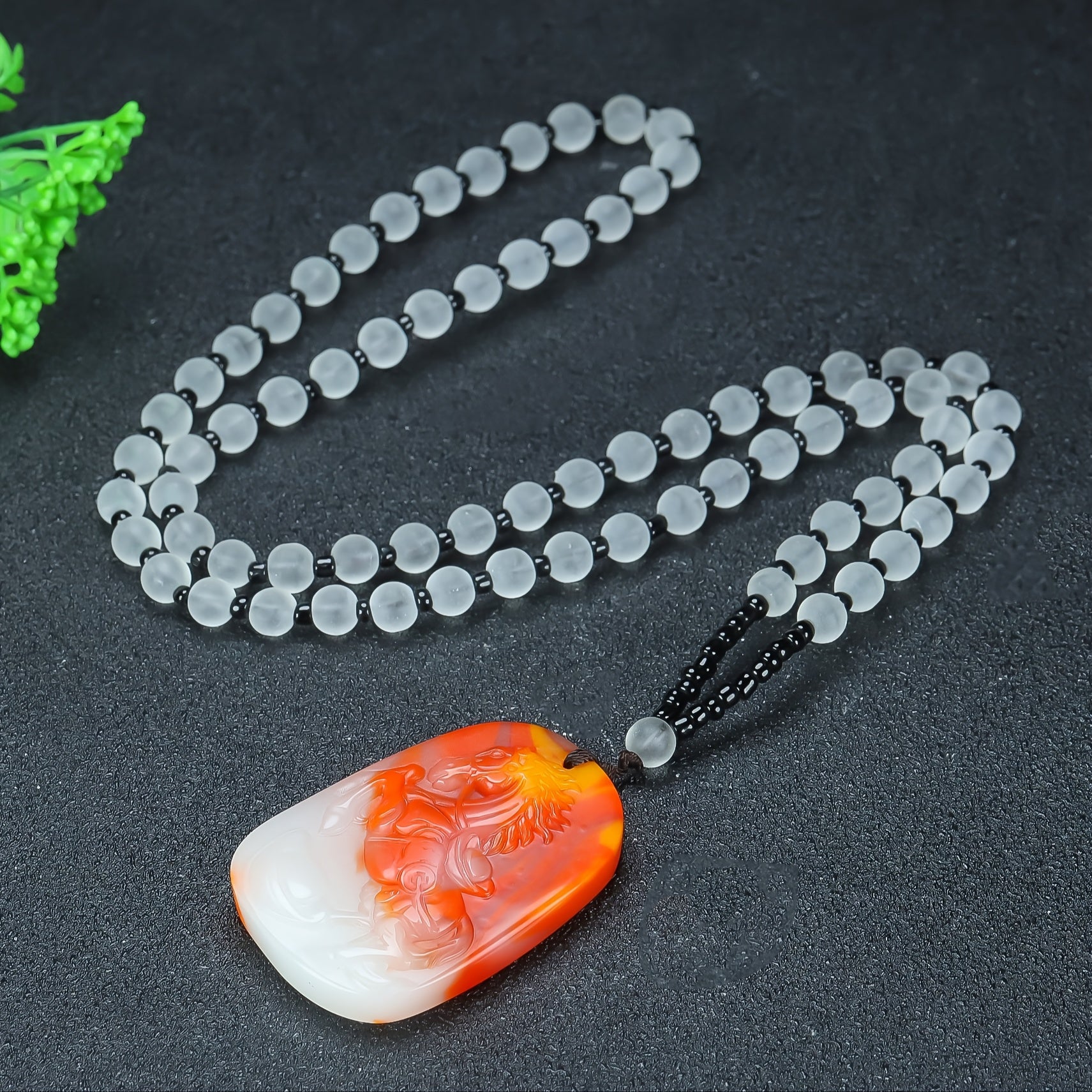 A vibrant red and white agate pendant carved with a dynamic horse