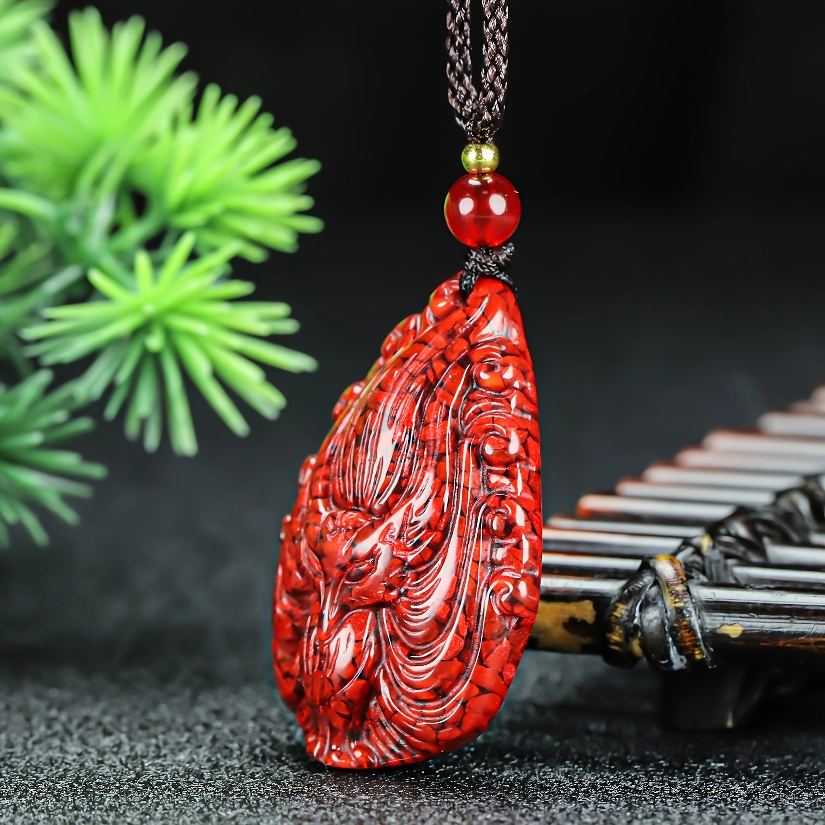 The pendant held in hand, highlighting its natural cinnabar texture
