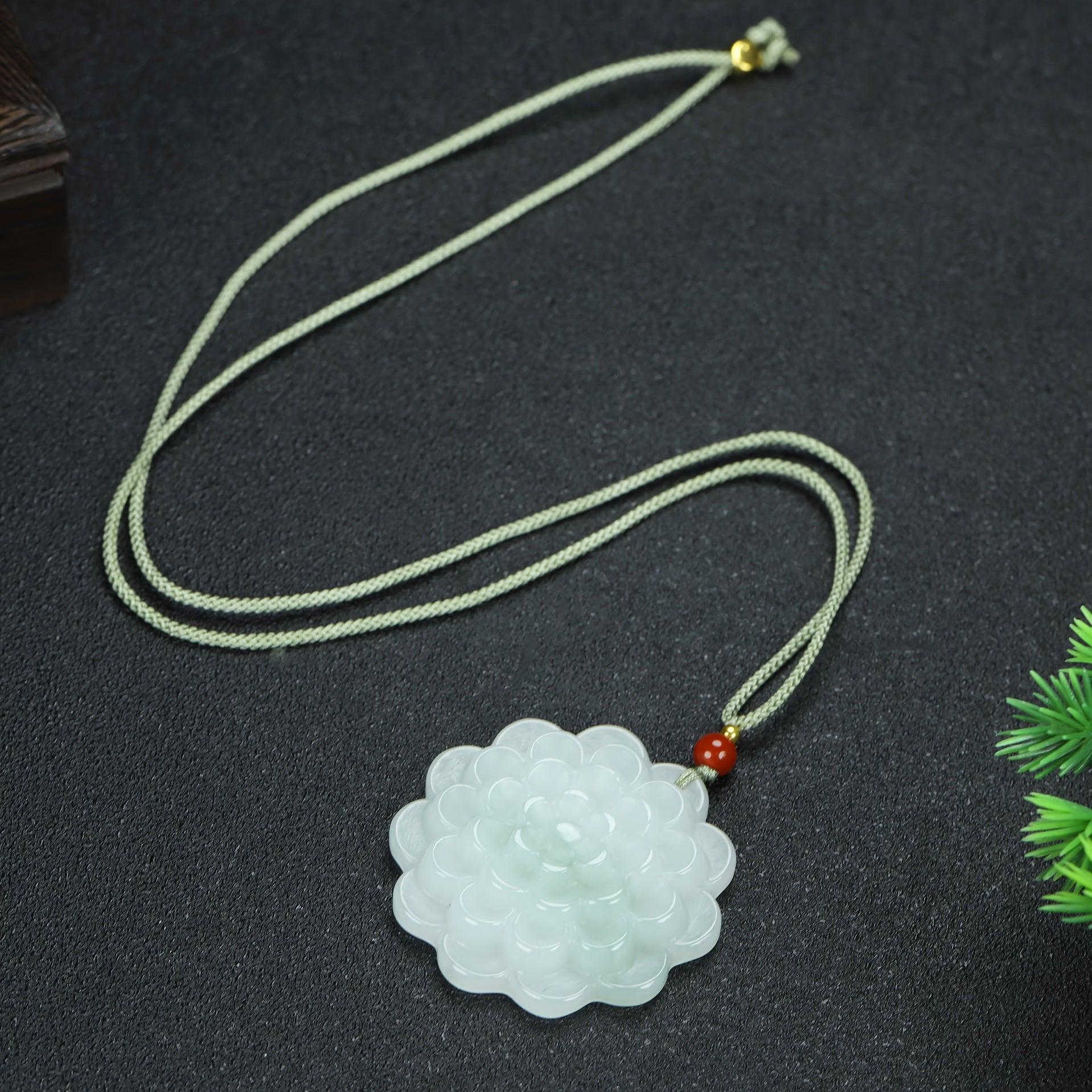 Close-up of the intricately carved peony pendant showing detailed petals