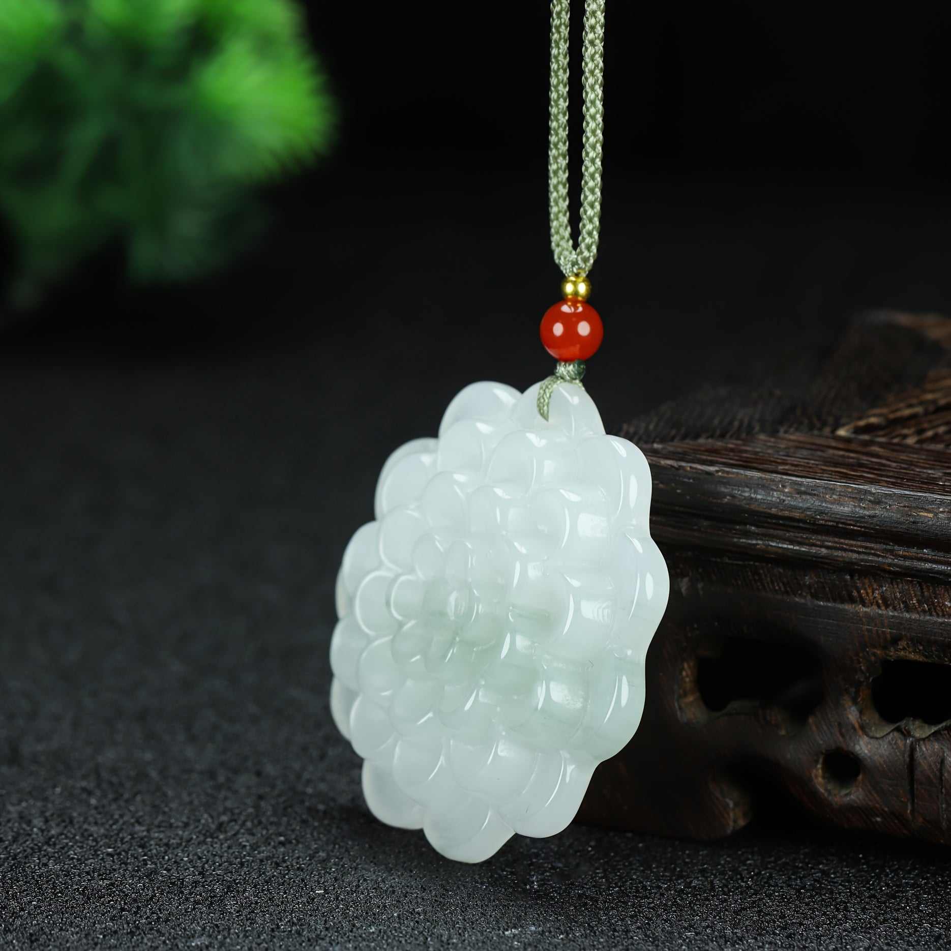 The pendant in natural light showing stone texture and carving depth